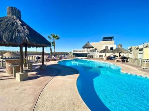 uma piscina com guarda-sol e cadeiras de palha em Bella Vista 6 em Puerto Peñasco