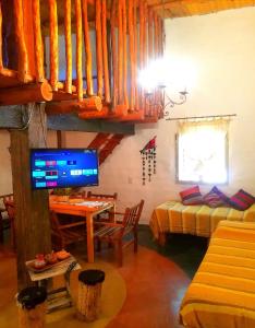sala de estar con TV, mesa y cama en Cabañas Paqa Paqa en Maimará