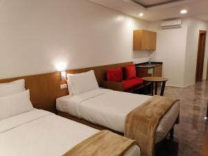 a hotel room with two beds and a red chair at Casa City Break Appart hôtel in Casablanca