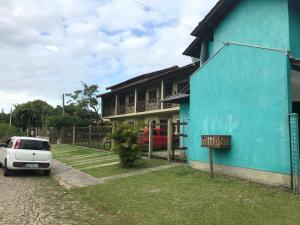 a blue house with a white car parked in front of it at Pousada Recanto da Barra Imbé in Imbé