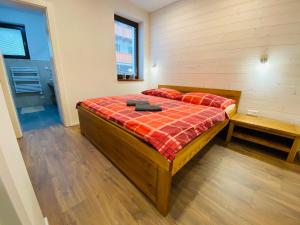 a bedroom with a bed with a red plaid blanket at Apartmán Večernica Trangoška Chopok Jasna Juh in Tale +28 photos