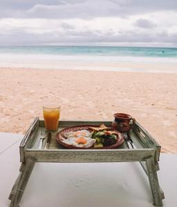 a tray of food and a drink on the beach at Alquimia Hotel Boutique in Tulum