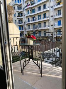 a table and chairs on a balcony with a building at Cozy studio with a sea view in Nice