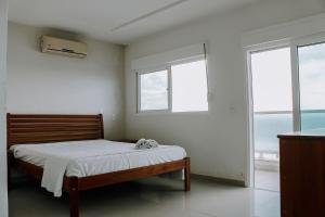 a bedroom with a bed and two windows at Casa beira mar na Praia da Redinha by Qavi in Natal