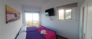 1 dormitorio con cama morada y ventana en Buenavista, en La Frontera