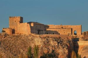 un castillo en la cima de una colina con una montaña en VIVIENDA VACACIONAL EL MOLINO ARGAMASILLA DE ALBA, en Argamasilla de Alba