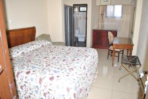 a bedroom with a bed and a desk and a bathroom at International Hotel, Yaoundé in Yaoundé