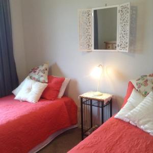 クロムウェルにあるSabai sabai 27のベッドルーム1室(赤いベッド2台、鏡付)