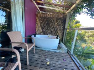 una vasca da bagno situata su una terrazza con tavolo e sedie di Orquídea Café a Guarapari