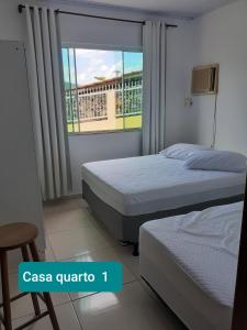 a bedroom with two beds and a window with a balcony at Residencial Di Paoli in Bombinhas