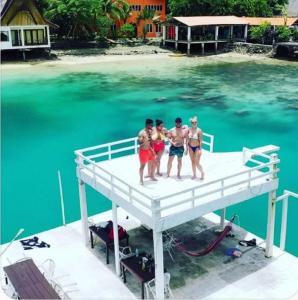 un grupo de cuatro hombres parados en un muelle en el agua en Club Tara Island Resort, en Socorro