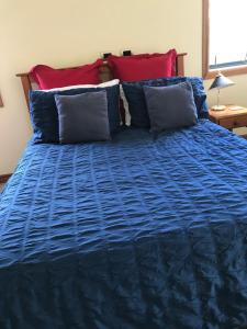 a bed with blue sheets and red pillows at Pilgrims Rest in Miranda