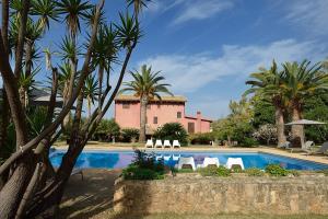 a swimming pool with chairs and palm trees and a building at Casa Realia in Agrigento