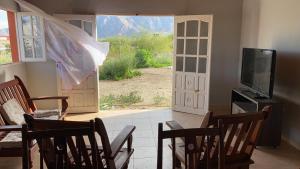 ein Wohnzimmer mit einem TV, einem Tisch und Stühlen in der Unterkunft Casa de Campo Vertientes in Cafayate