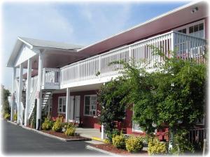 ein rot-weißes Gebäude mit Bäumen davor in der Unterkunft The Burgundy Inn Hotel and Apartments in Ocean City