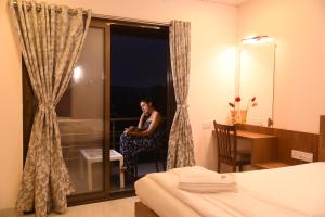 a woman sitting in a chair in a hotel room at Stone shelter in Mahabaleshwar