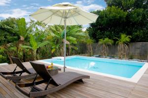 un patio con 2 sillas y una sombrilla junto a la piscina en Pool Villa Sesoko jima, en Motobu