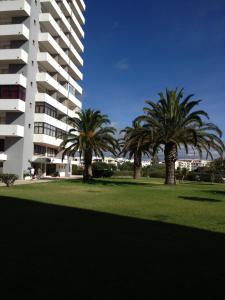 two palm trees in a park next to a building at Apartamento Praia do Alvor in Alvor
