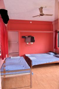 two beds in a room with red walls and a tv at Doctors Heritage Lodge in Sringeri