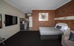 a room with a bed, a table and a wall at Albury Townhouse Motel in Albury