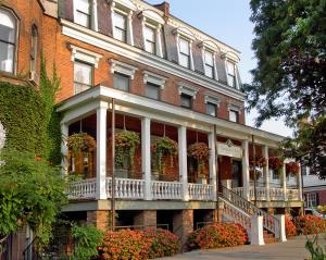 a large brick building with a porch and flowers at Saratoga Arms in Saratoga Springs