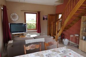 a living room with a tv and a staircase at Gîte du Vieux Chemin in Durbuy