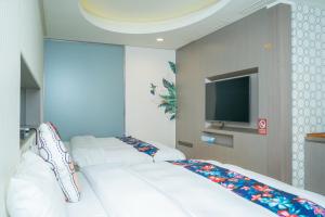 Cette chambre comprend 3 lits blancs et une télévision à écran plat. dans l'établissement 日月潭天月水色民宿 (老街-停車-度假）skylight bnb, à Yuchi