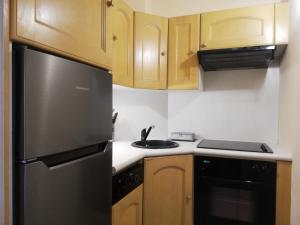 een keuken met houten kasten en een zwarte koelkast bij Appartement Le Belvédère in Roquebrune-Cap-Martin +24 foto's