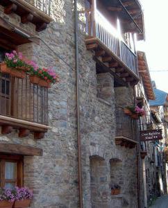 un edificio de piedra con balcones y flores. en Casa Rafeleta Hotel en Plan