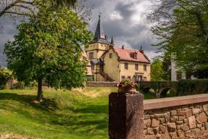una casa antigua con una torreta y una valla de piedra en Wasserschloss Podelwitz en Colditz