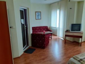 een woonkamer met een rode stoel en een televisie bij Хотелски Комплекс Авалон in Asenovgrad