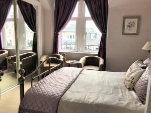 a bedroom with a bed and two windows at The Castle B&B in Inverness