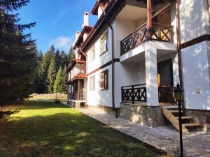 a white house with a porch and a yard at Приказното място - The Fairytale Place in Smolyan