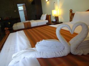 Dos cisnes hechos de toallas en una cama en The Chevalley Beach Resort, en Satun