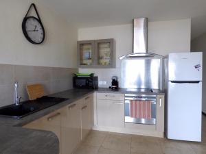 a kitchen with a refrigerator and a clock on the wall at La douceur du lagon in La Saline les Bains