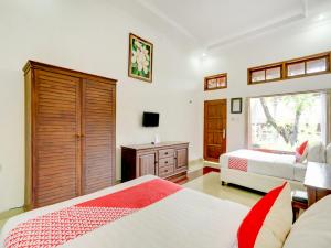 a bedroom with two beds and a dresser and a window at SUPER OYO 3261 Hotel Ratu in Denpasar