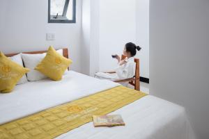 a woman sitting in a chair next to a bed at Kim Hoàn Hotel Phan Rang in Phan Rang