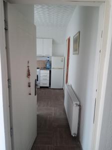 a hallway leading to a kitchen with white appliances at Apartman Visnja in Crni Vrh