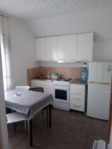 a kitchen with white cabinets and a table and a refrigerator at Apartman Visnja in Crni Vrh