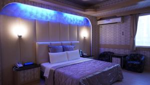 ein Schlafzimmer mit einem Bett mit blauem Licht darüber in der Unterkunft Wind Coast Motel in Hsinchu