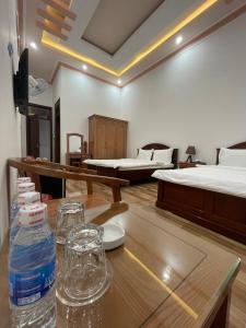 a room with two beds and a table with a bottle of water at Khách sạn Nguyên Long in Bao Loc