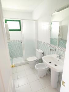 a white bathroom with a toilet and a sink at Apartamentos Babalu in Puerto Rico de Gran Canaria