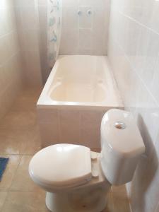 y baño con aseo blanco y bañera. en Hostal Nichkito, en Uyuni
