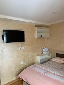 a room with two beds and a flat screen tv on the wall at Apartmani Ristanović in Zlatibor