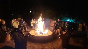 a group of people sitting around a fire pit at night at Ranthambhore Bagh Dwar Camp in Khilchipur +58 photos