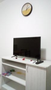 un televisor en una mesa blanca con un reloj en la pared en Apartman Jevtić 2 en Gornja Toplica