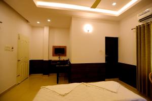 a bedroom with a bed and a desk and a television at SAPPHIRE INN in Nedumbassery