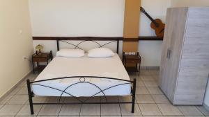 a bed with two pillows and a guitar in a room at TK-George Apartments by the Airport in Markopoulo