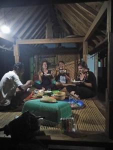 Un gruppo di persone seduti intorno a un tavolo che mangiano di Budaya Kaki Rinjani a Senaru