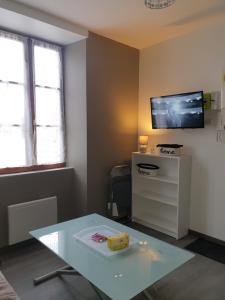 een woonkamer met een tafel en een tv aan de muur bij studio meublé au RDC , proche lac in Aix-les-Bains